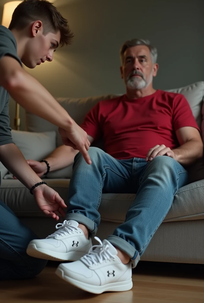 17 year old male blue eyes taking off his 39 year old male brown hair british neighbours white under armour trainers as the neighbour is sat om the sofa at home wearing a a red t-shirt and jeans 