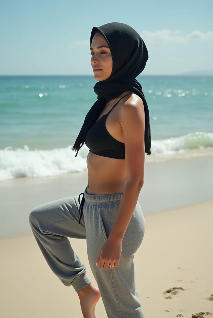 with black headscarf, grey sweatpants, barefoot woman without bra, sunbathing on the beach