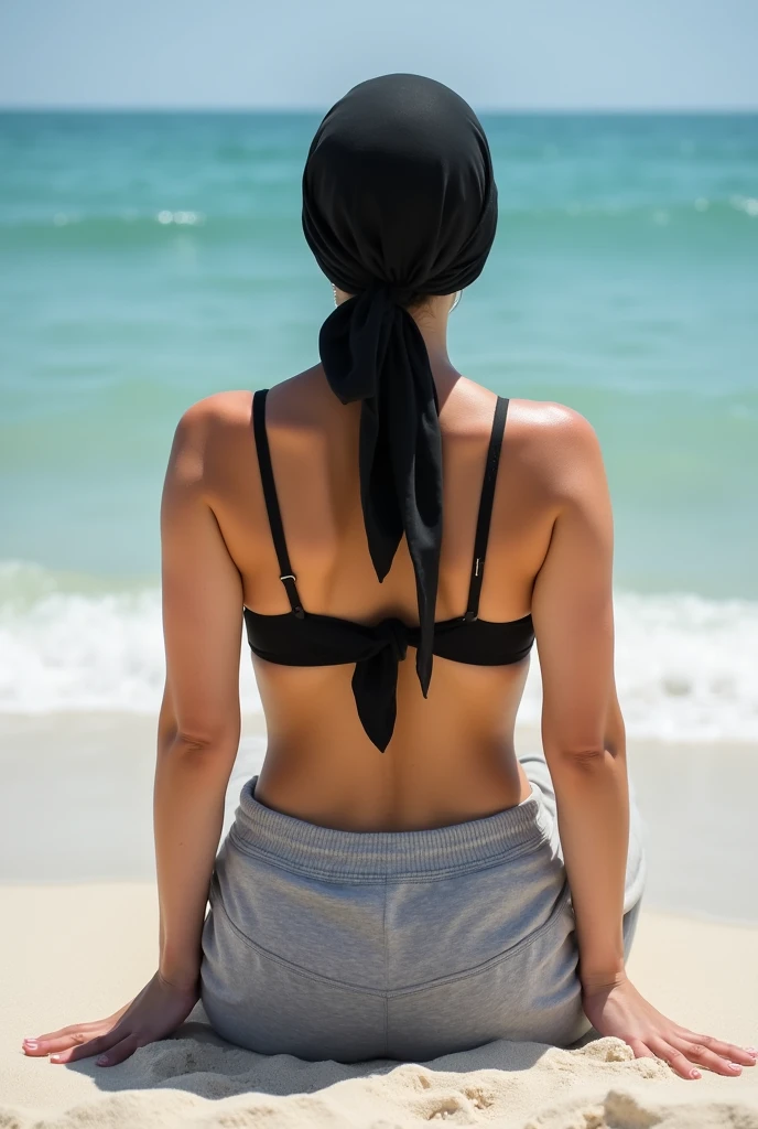 with black headscarf, grey sweatpants, barefoot woman without bra, sunbathing on the beach