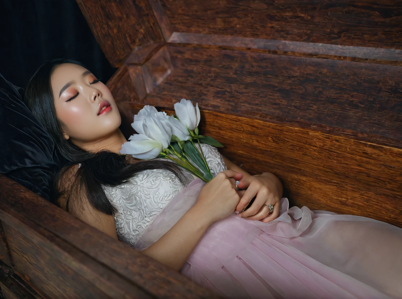 In a striking 8K HDR scene, a stunning Korean woman, 22 years old, lies peacefully in a coffin and coffin cover surrounded by plush pillows behind head. The deep box is set against a rich black background, accentuating the beauty of the subject. Her exquisite deep-V neckline kebaya attire is embroidered with superb detail, showcasing her round and firm breasts, perfect cleavage, and beautiful eyebrows. Her closed eyes and mouth give an air of serenity, while her visible and absolute cleavage leave nothing to imagination. The scene is bathed in saturated colors, highlighting every intricate aspect from the ball skirt to her clean face, straight body, detailed hand perfect hands, straight body, own hands together, own hand on stomach, detailed hands, perfect hands, holding the flowers.