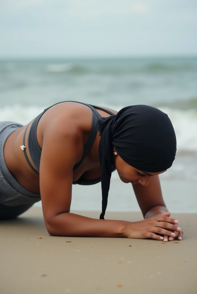 with black headscarf, barefoot, grey sweatpants, braless woman, lying face down on the beach