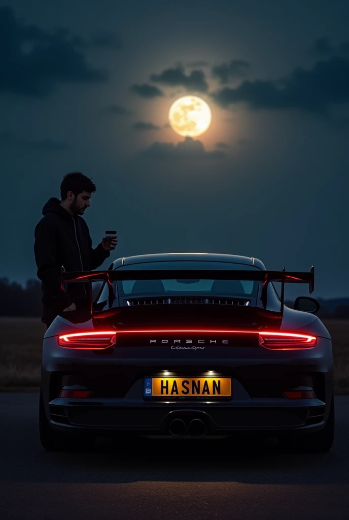 A black porsche with drls on in the dark night with a shining moon in the back and a name HASNAN on the number plate with a guy standing infront of it with a cup of coffee