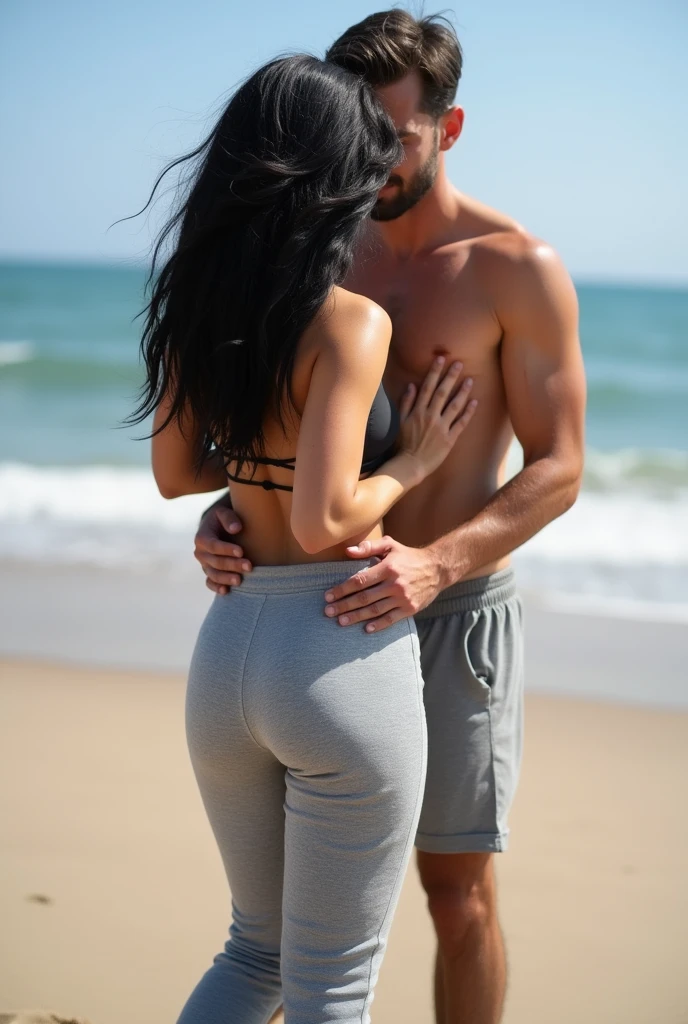 Black wavy hair on the beach, grey sweatpants, Barefoot woman. Man touching woman&#39;s butt