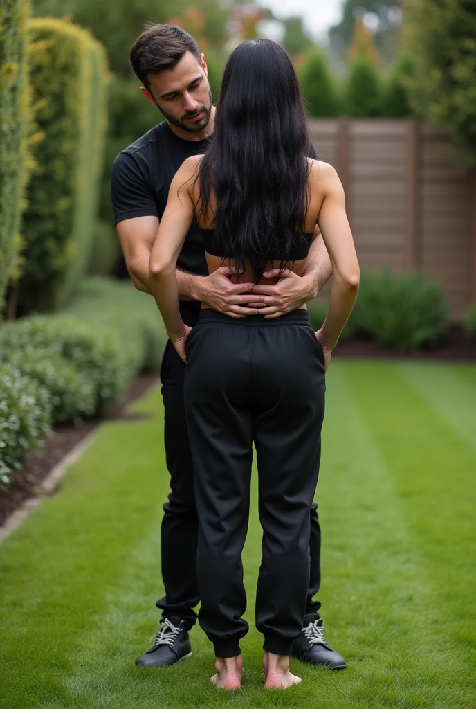 Black hair in the garden, black sweatpants , Barefoot woman. Man pressing woman&#39;s butt from behind