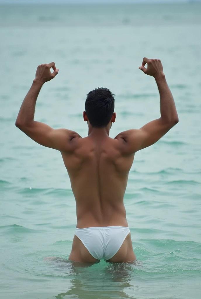 A man takes off his shirt, is playing in the water, wearing underwear, white skin, raising both thin arms, white underwear, facing away.