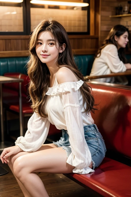 The image is a portrait of a young woman sitting on a bench in a restaurant. She is wearing a white blouse with ruffled sleeves and denim shorts. Her long brown hair is styled in loose waves and falls over her shoulders. She has a serious expression on her face and is looking off to the side with a slight smile. The background is blurred, but it appears to be a busy restaurant with other people sitting in the background. The overall mood of the image is relaxed and casual.