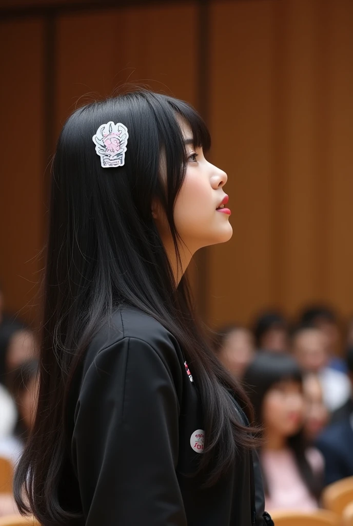 kpop female auditions in a hall. a girl with long black hair have sticker sticked on her top singing. judges sitting in front of her
