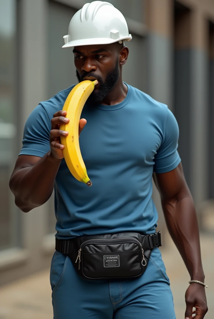 Black man wearing blue pants and t-shirt, white construction helmet and black fanny pack eating a large banana
