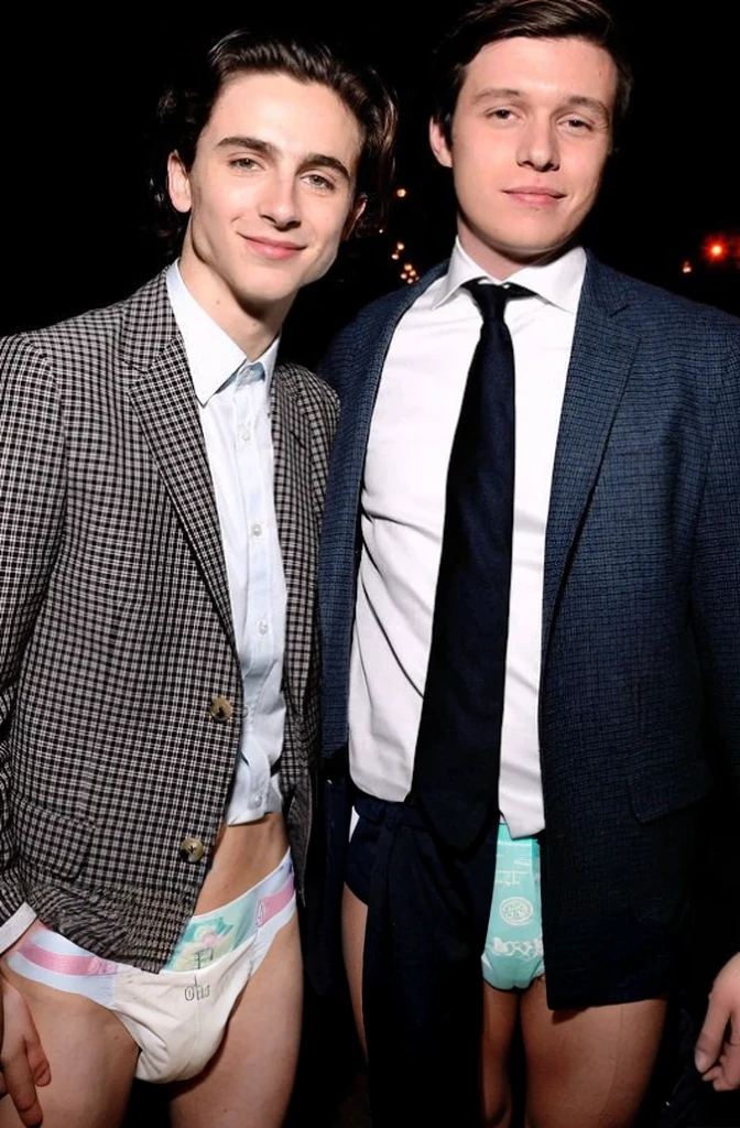 Two young men standing next to each other, very skinny, bare legs, wearing a diaper 