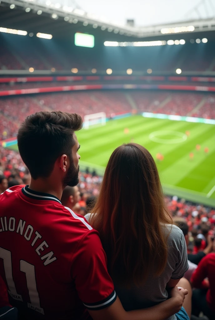 A man and a woman wearing a Manchester shirt watching the ball in the stadium