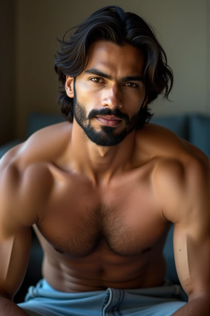 26 years old Indian, mascular, medium hair and beard, brown eyes and hair, soft lips, fair skin tone, sitting in a couch, looking into the camera.