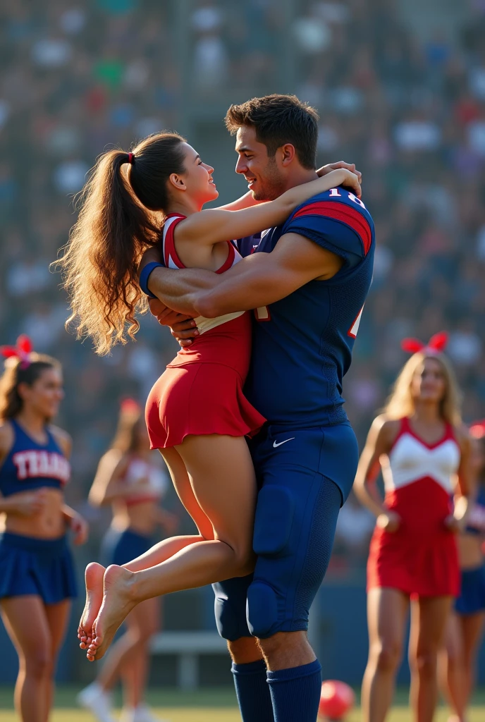 Beautiful barefoot cheerleader in red cradle carrying a muscular handsome football quarterback. Woman carrying football player. Football player in blue uniform. Football player completely off the ground. Cheerleaders in background.