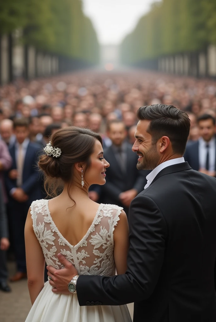 A married couple talking with a large crowd of people in the background behind them.