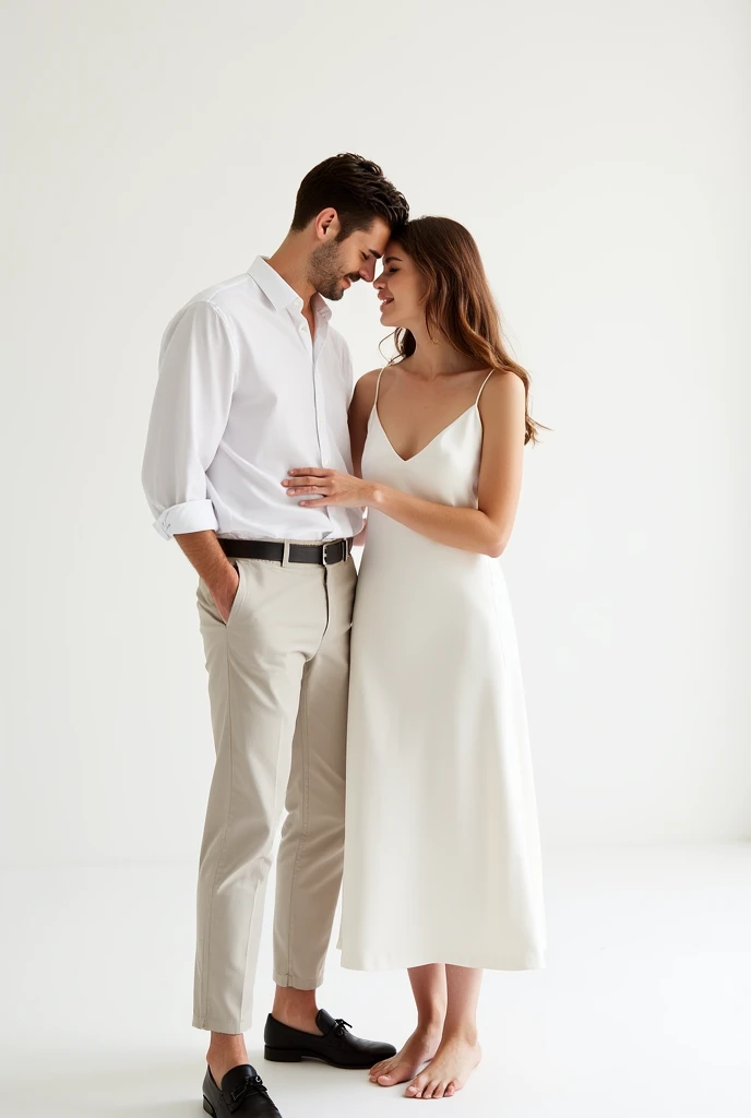 A wedding photo shoot set against a plain white background with no props or additional elements. The bride wears a minimalist white dress from Zara, such as a sleeveless or spaghetti-strap slip dress with a satin or crepe finish. The dress has a clean, elegant silhouette that flows naturally, hitting just above the ankle or at a midi length. Her hair is styled loosely, either left down with soft waves or in a simple, low bun. Her makeup is minimal, emphasizing her natural beauty with a soft glow and neutral tones.
The groom complements her look with a casual yet refined outfit. He wears a crisp white shirt, either tucked into light-colored chinos or paired with slim-fit dark trousers, both options available from Zara. The overall look is polished but relaxed, reflecting the couple's modern and understated style.
In the photo, the couple stands close together, with the groom gently holding the bride's hand or wrapping his arm around her waist. Their expressions are warm and genuine, capturing their natural chemistry. The clean white background highlights the simplicity and elegance of their attire, focusing entirely on their connection and the purity of the moment