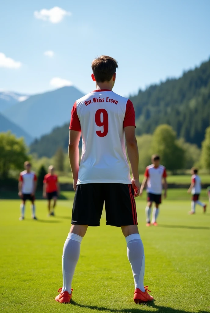 A 17 year old football player training at a training camp ,Wearing a white and red jersey,Number 9, The jersey says Rot-Weiss Essen , photographed from behind 