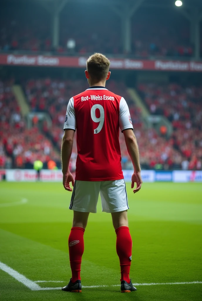 A 17 year old soccer player who is taking a free kick, Wears a red and white jersey with the number 9,The jersey says Rot-Weiss Essen, photographed from behind