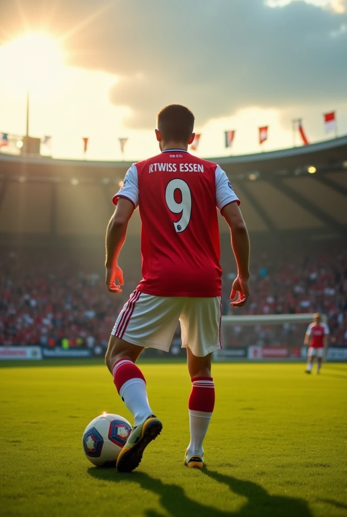 A 17 year old soccer player who is taking a free kick, Wears a red and white jersey with the number 9,The jersey says Rot-Weiss Essen, Photographed from behind in a small stadium