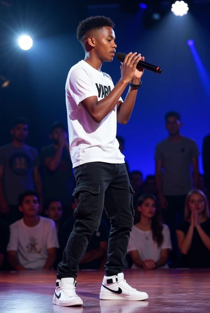 **Image Description**:
A 17-year-old rapper is performing on stage during an audition, with his look clearly visible on camera. He is wearing black cargo jeans, OGIY sneakers, and a white hip-hop T-shirt with "YABU" written on it. His haircut is a 0 on the sides with a slight slope. He holds a microphone in his hand and is deeply engaged in his performance. Three judges, seated at a table in front of the stage, watch him intently. The audience is visible in the background, observing from the side. The stage is brightly lit, emphasizing the rapper's dynamic and energetic presence.