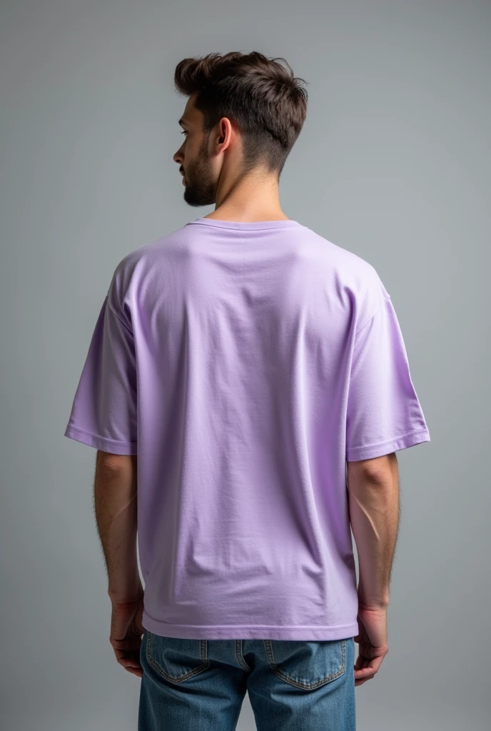 Handsome man,  standing straight facing at back,wearing  levendar colour oversized t-shirt, denim pants, against greyish background, cotton texture of t-shirt, oversized tshirt,round neck, half sleeves. Cotton texture of t-shirt should be visible little bit.