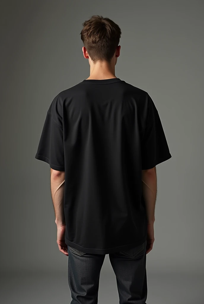 Handsome man, standing straight facing at back wearing black colour oversized t-shirt, denim pants, against greyish background, cotton texture of t-shirt, oversized tshirt,round neck, half sleeves. Cotton texture of t-shirt should be visible little bit. Hands should be straight.