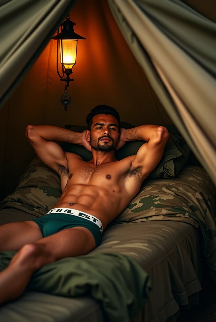 Hot and handsome indian army officer with fully jacked muscular body laying on bed in a position where his both hands are behind his head inside the army tent wearing brief jocks.