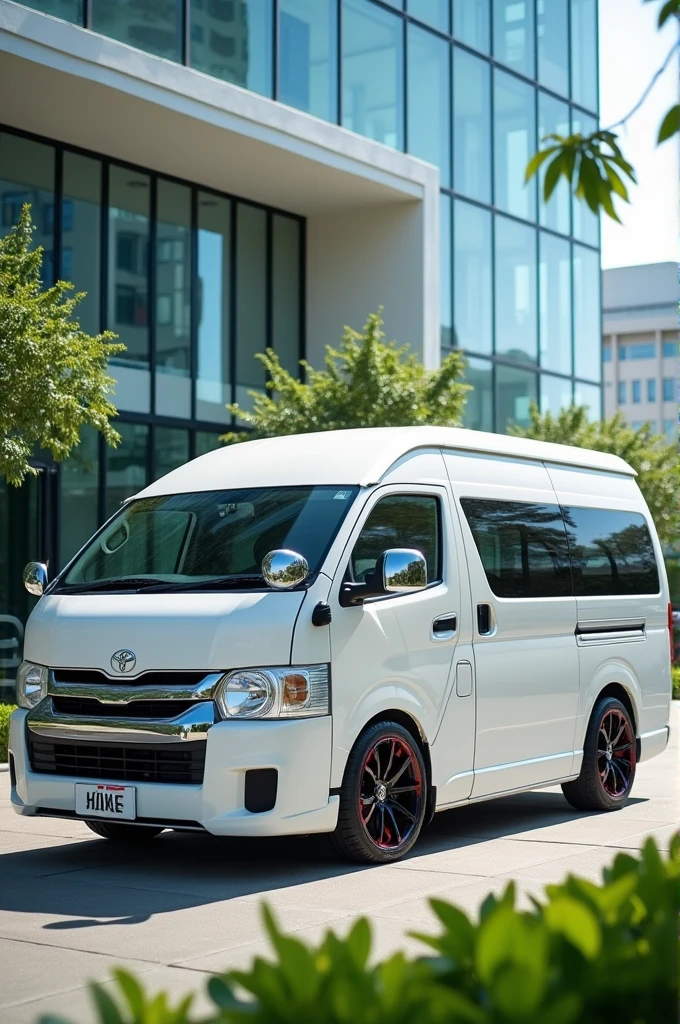 The image is a rendering of a white Toyota Hiace van. The van is parked in front of a modern building with a glass facade. The front of the van has a sleek and modern design with a large front grille and a curved roofline. The Toyota logo is prominently displayed on the side of the vehicle. The vehicle has black rims and red brake calipers. The background is blurred, but it appears to be an outdoor setting with trees and a blue sky.
