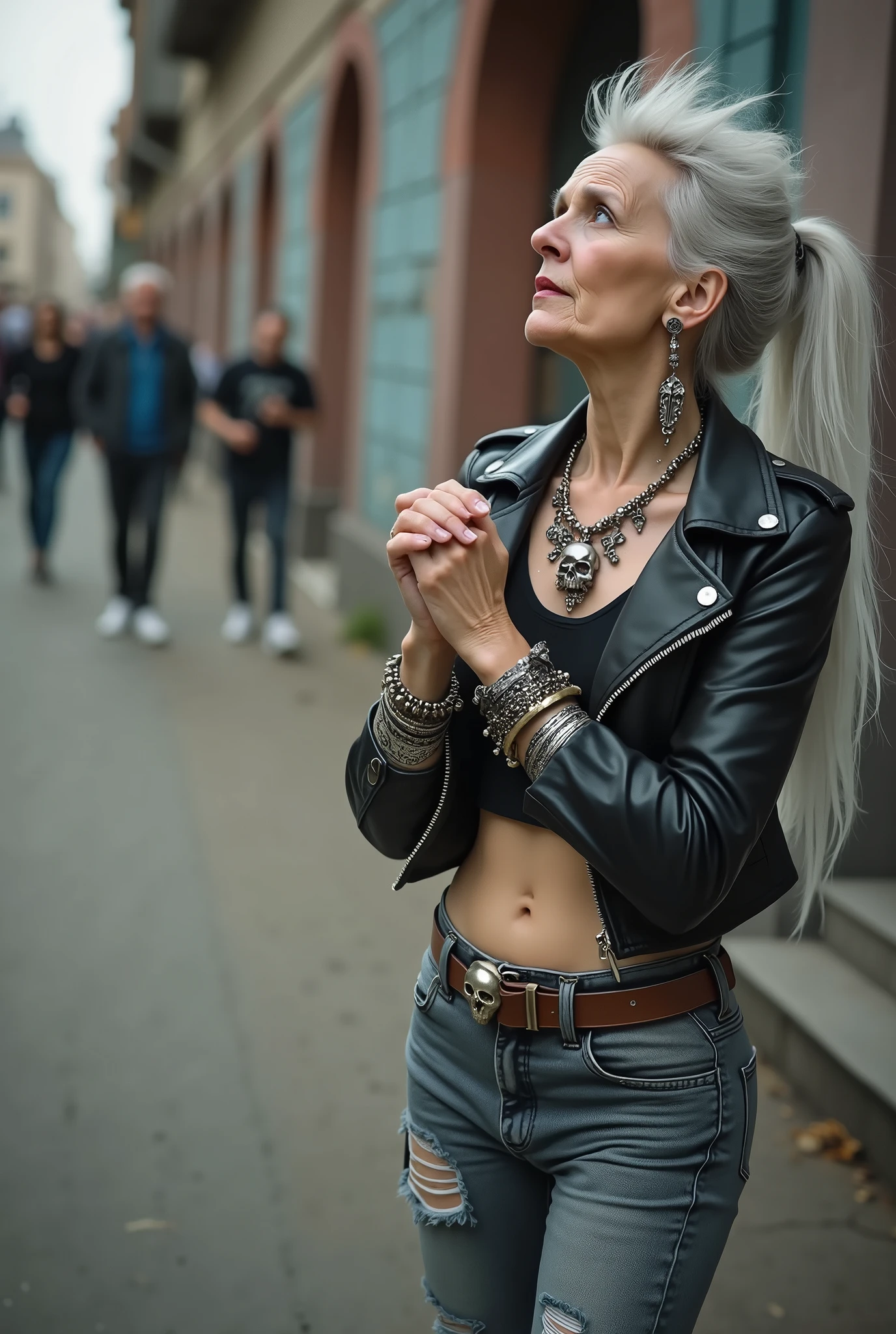 russian old milf woman, biker gang member, long grey hair (bump, quiff and ponytail) with very light blue eyes, extremely pale. Thin. Sad, humble face. Wearing cropped black moto jacket with side zippers, black cropped tank top with pentacle logo, skinny black jeans with holes and white tennis sneakers. Lots of metallic bracelets. Chains. Tacky studded leather wide belt with massive skull and bones buckle . Both hands in prayer. Demonic tattoos. Lots of rings. Long earrings. Looks up with amazement because she thinks God is talking to her, mouth and eyes open. Skinny legs, narrow hips. People  near her are looking at her