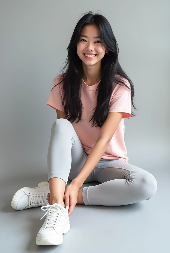 Full body image of black-haired woman wearing a pink shirt with white short sleeves sitting in light gray sports leggings and white tennis shoes 

