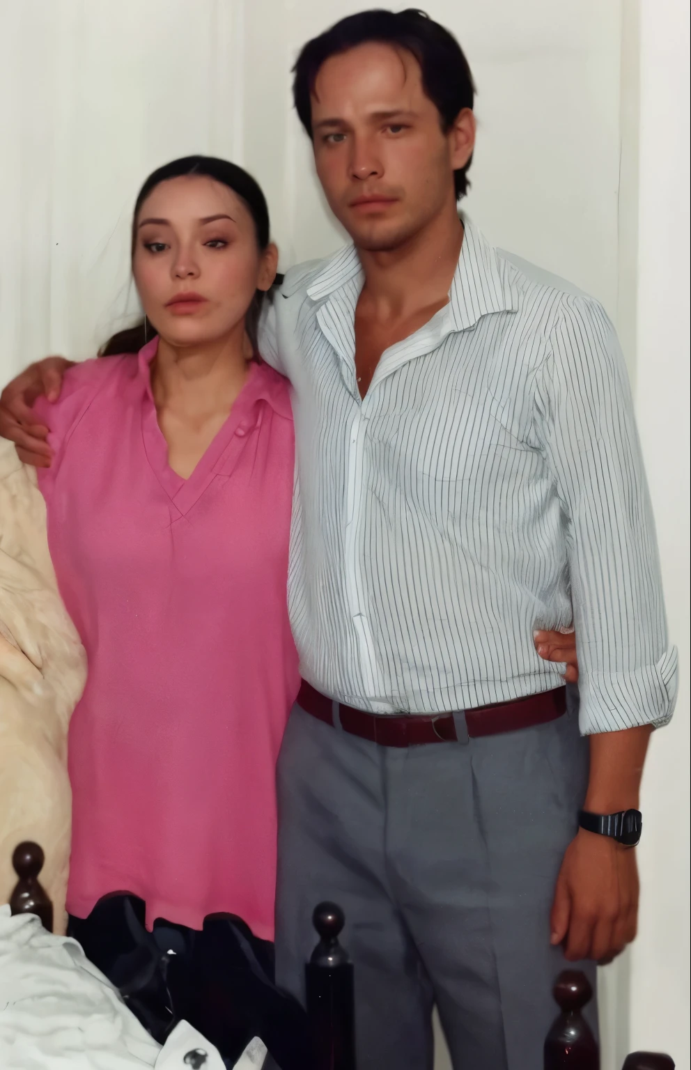 The man's shirt is light-black, his pants are black, his hair is curly black, and he has a watch on his left hand. The woman is wearing a light-purple dress, her hair is black, and she is wearing a watch on her right hand. Both are a couple. The color of the skin is Black. The floor is an old house indian cupple