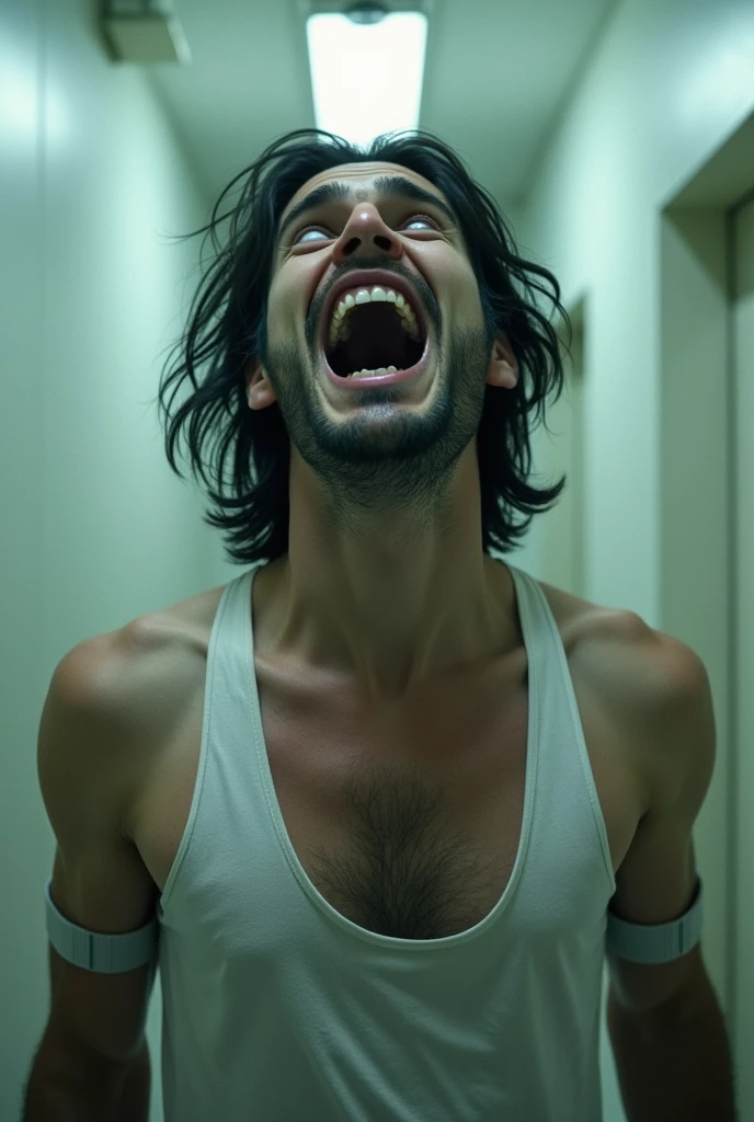 Handsome and sexy crazy man laughing in a mental asylum with a long white straitjacket
