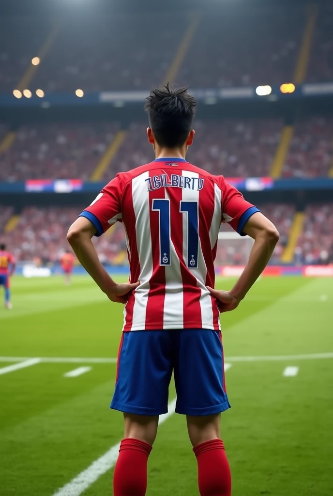High quality photography, of a full-length 19-year-old boy playing soccer, He is standing with his hands on his waist about to kick a free kick with his back turned, with the name Gilbertoy and the number 11 on his back, He has black hair that is a bit big, with the Atlético Madrid uniform Super realistic