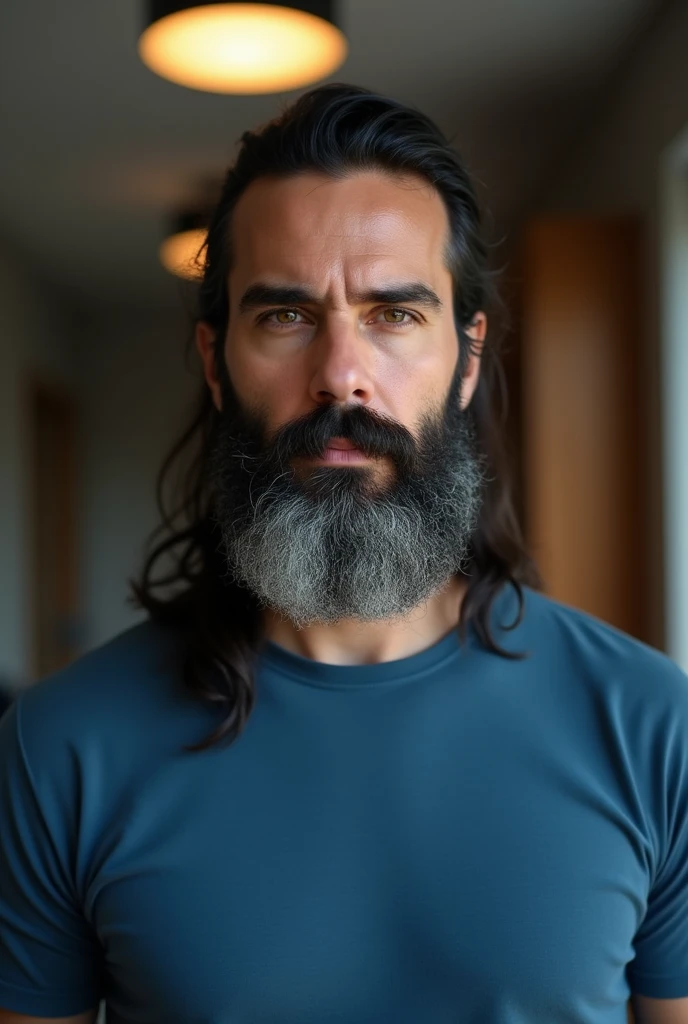 A hyperrealistic portrait of a bearded man with long hair tied back, looking directly at the camera with a focused expression. He has dark hair with streaks of gray, especially in his beard. He is wearing a blue t-shirt. The background features a home interior with muted lighting, modern furniture, including a ceiling light fixture, and a wooden cabinet on the right side.