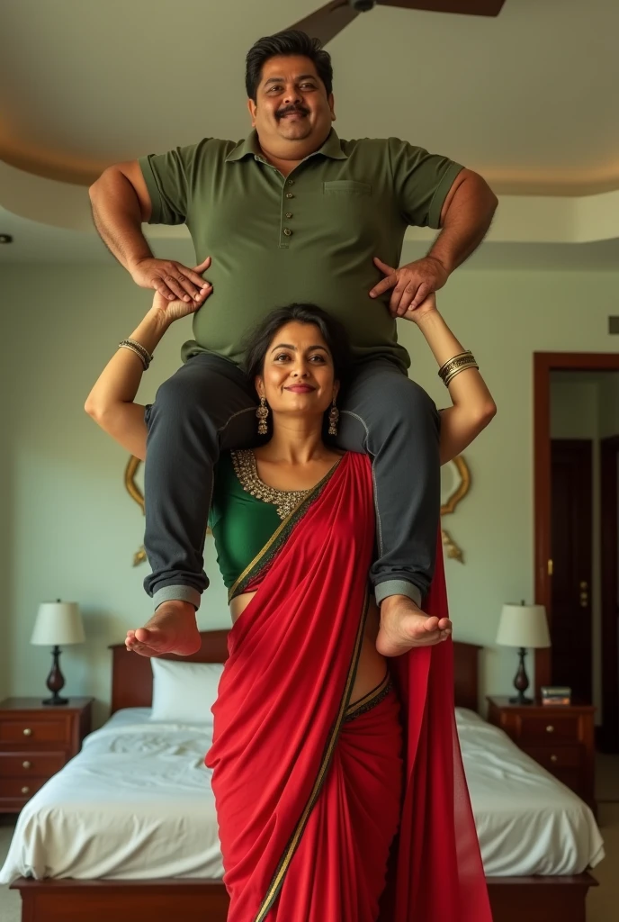 Beautiful and Slim Indian woman Aishwarya Rai in green blouse red saree lifting a large chubby man above her shoulders, man is sitting on woman's shoulders, in a bedroom with high ceiling, natural smile, woman is looking into the camera , full body image