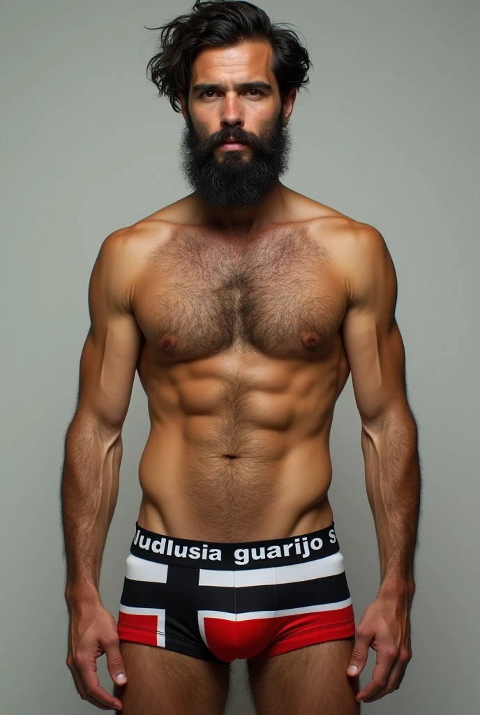 Hairy, bearded mixed-race man wearing underwear printed with the flag of the State of Prussia, with the word “GUARIJO” written in large letters on the elastic of the underwear.
