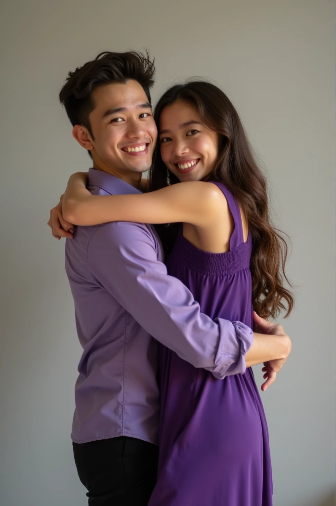 A young man holding a young woman by the waist, she in a purple dress and he in a purple shirt and black pants