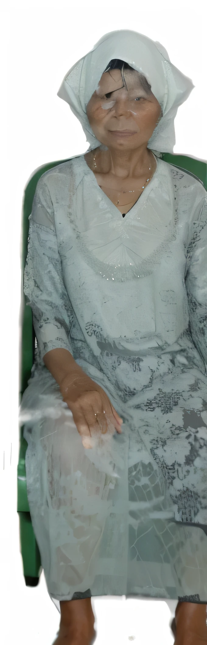 A grandmother from Indonesia was sitting on a green plastic chair wearing a white headscarf and a grey shirt