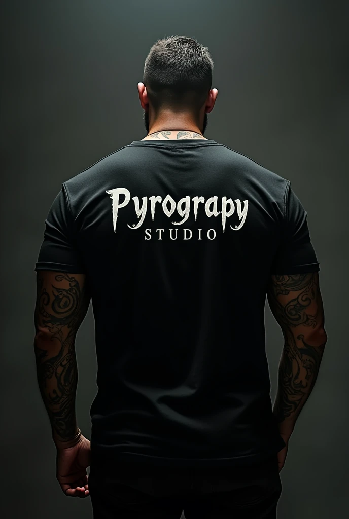 Dark-skinned, tattooed man from behind wearing a black t-shirt with the legend Pyrograpy Studio 

