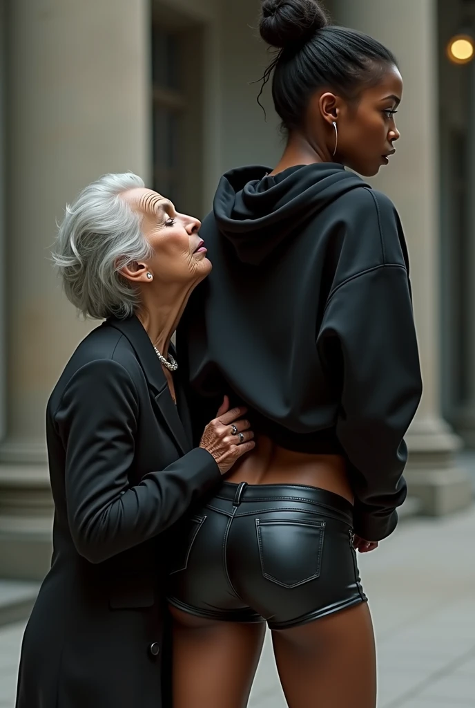 black woman hair in a bun black hoodie black leather short shorts rea;;y in shock as a old grandma in a dress on her knees kissing her ass behind her hand is in her ass holding her ass
