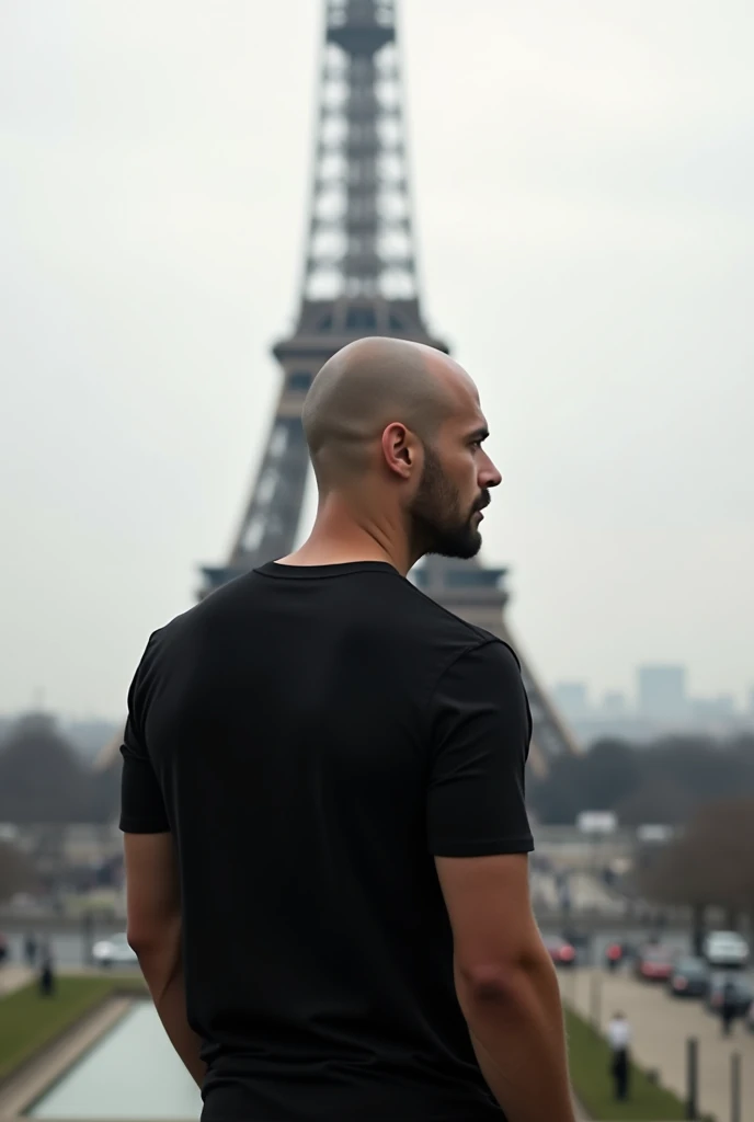 create a realistic photo of a bald man in Paris. showing the Eiffel Tower, he is completely turned away, you can&#39;t see his face,  of costs for a camera, wearing a chic basic black t-shirt.  white in color and the tower far from the photo