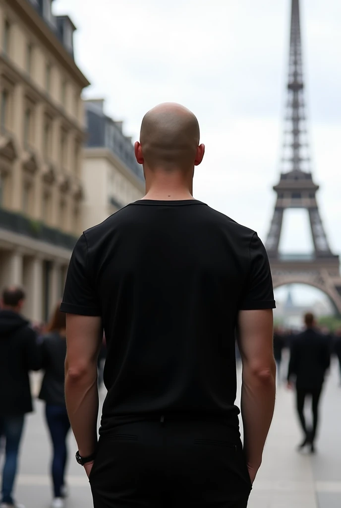 create an ultra modern realistic image of a bald man in Paris. he is completely turned away, you can&#39;t see his face,  facing away from the camera, wearing a chic basic black t-shirt.  white in color and the tower away from the full body photo 
