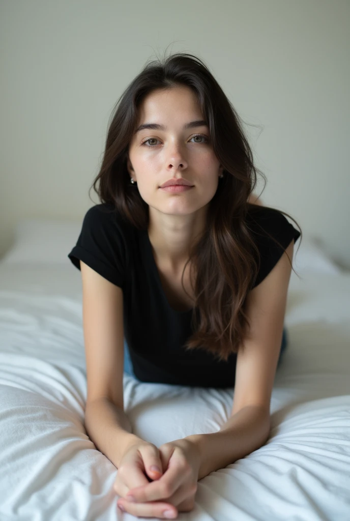 brunette, smile, flat chest, skinny face, white wall, no decoration, jean shorts, black t-shirt, lying on stomach on bed, looking at camera, photo from behind