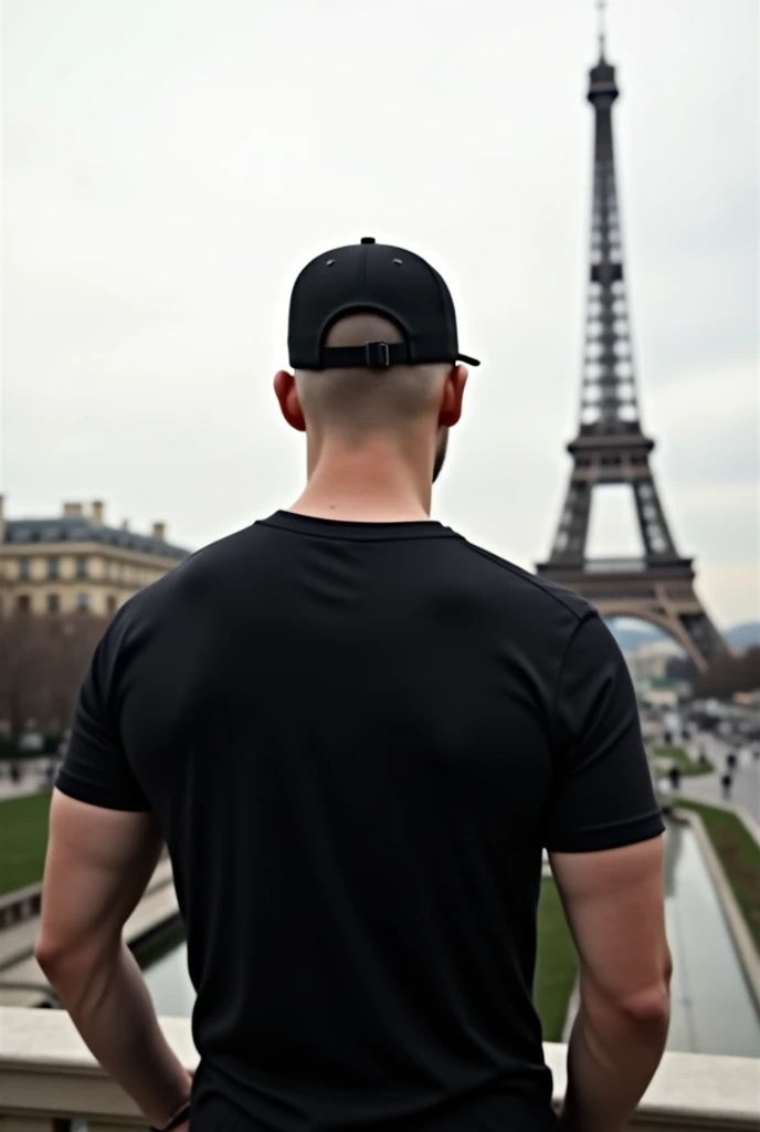an ultra modern realistic image of a bald man in Paris. he is completely turned away, you can&#39;t see his face,  facing away from the camera, wearing a chic basic black t-shirt.  white in color and the tower away from the full body photo add a black cap with the brim turned towards the back