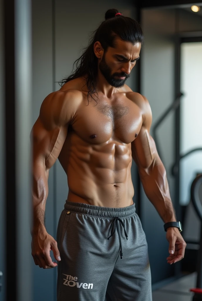 A smart indian men with long hair, wearing track pant with text "THE ZOVEN" and doind workout