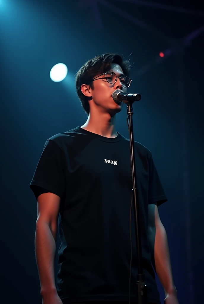 A handsome 1 boy with slight long hair, wearing a glasses singing Infront of mic wearing black t-shirt written "SEAG" on it