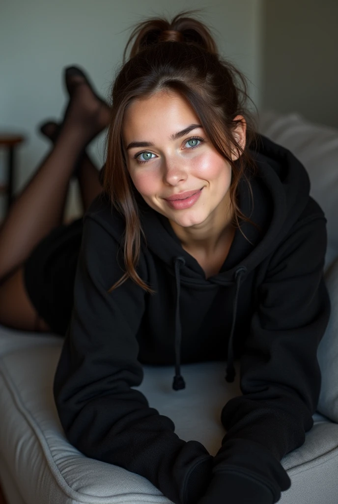 dark brown hair、pulled back ponytail、teaing smile、 she wears a black hoodie.、black pantyhose、adult german woman、blue eyes、showing her black pantyhose、lying on a couch、young german woman、wide angle、 she has ocean blue eyes.、