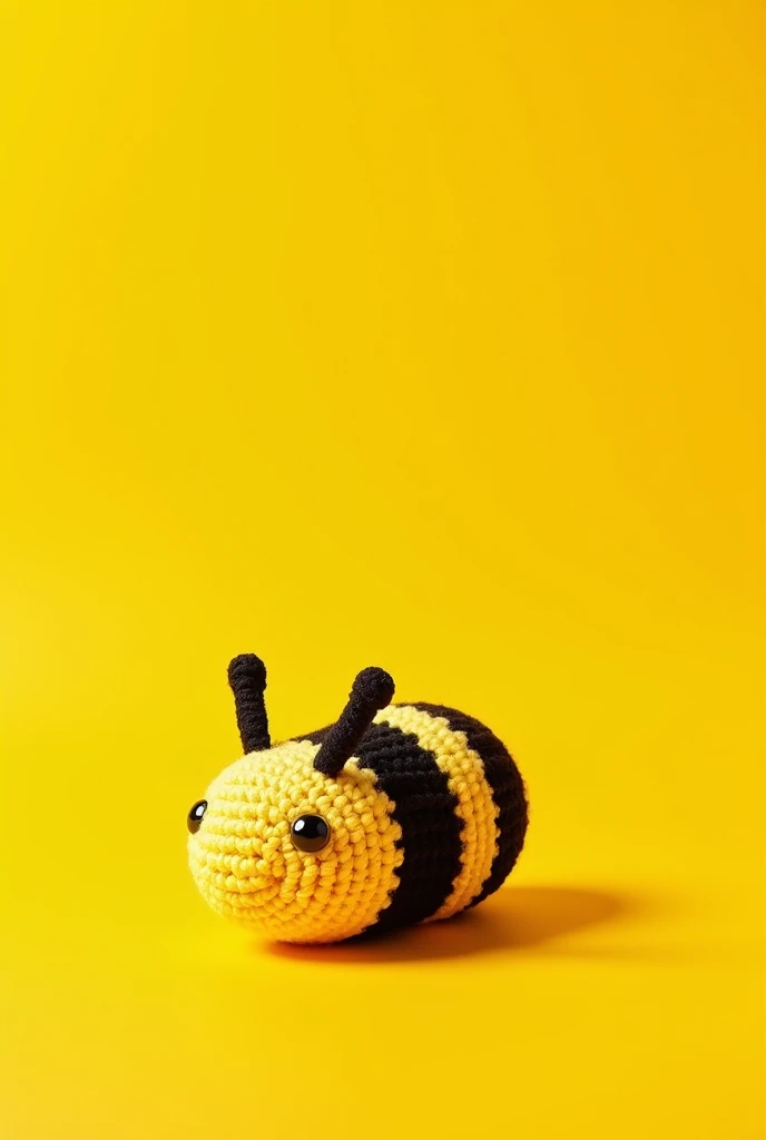A round crochet bee without mouth and legs and behind a yellow background 