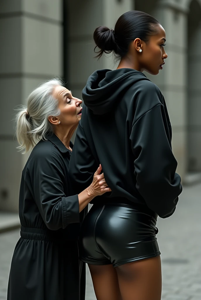 black woman hair in a bun black hoodie black leather short shorts rea;;y in shock as a old grandma in a dress on her knees kissing her ass behind her hand is in her ass holding her ass
