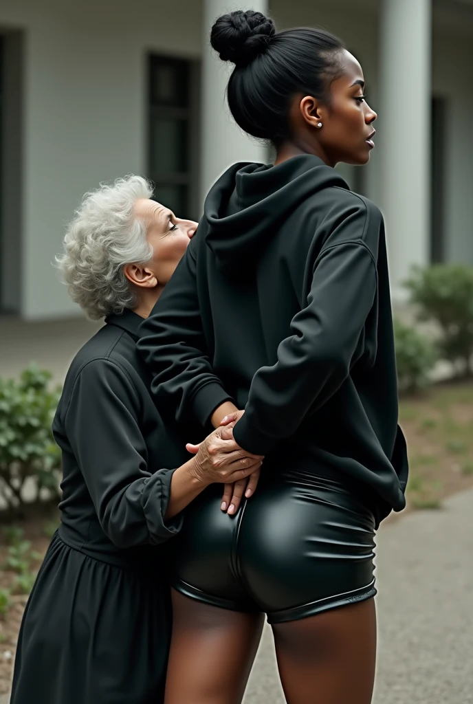 black woman hair in a bun black hoodie black leather short shorts rea;;y in shock as a old grandma in a dress on her knees kissing her ass behind her hand is in her ass holding her ass
