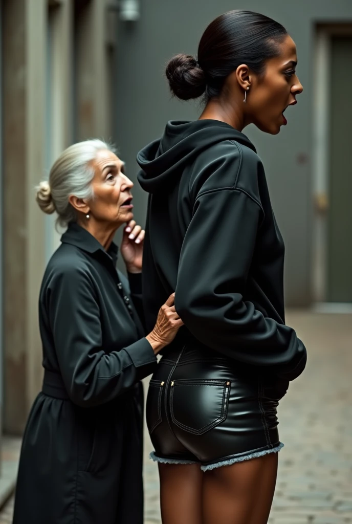 black woman hair in a bun black hoodie shiny black leather short shorts pockets in shock as a old grandma in a dress on her knees kissing her ass behind her hand is in her ass holding her ass 