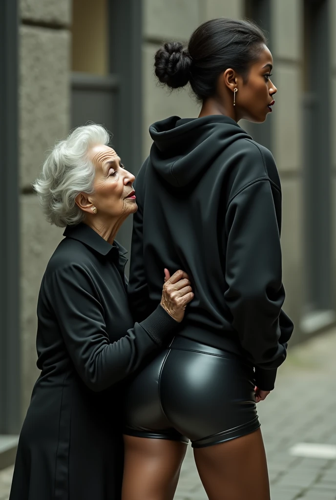 black woman hair in a bun black hoodie black leather short shorts rea;;y in shock as a old grandma in a dress on her knees kissing her ass behind her hand is in her ass holding her ass
